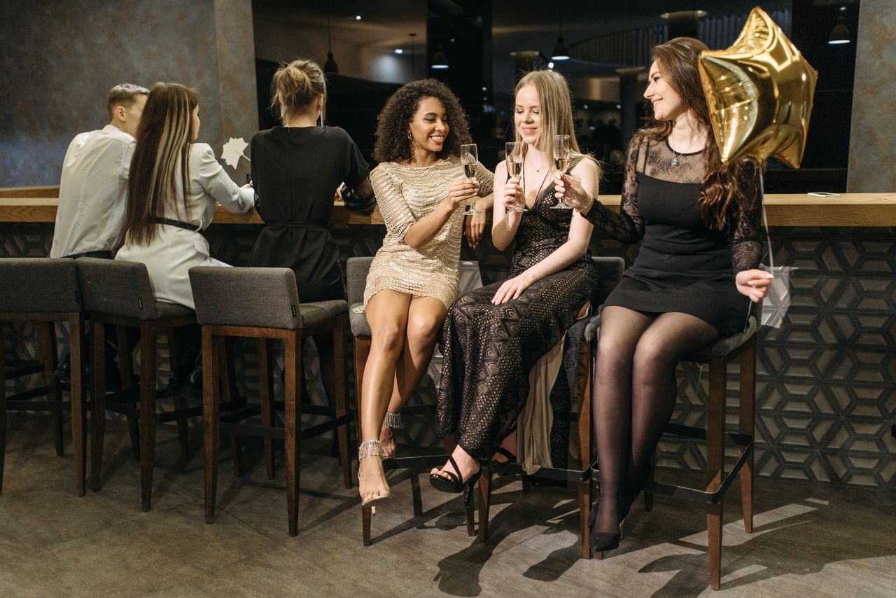 why-choose-us Women celebrating with champagne at a stylish indoor bar, showcasing diversity and friendship.